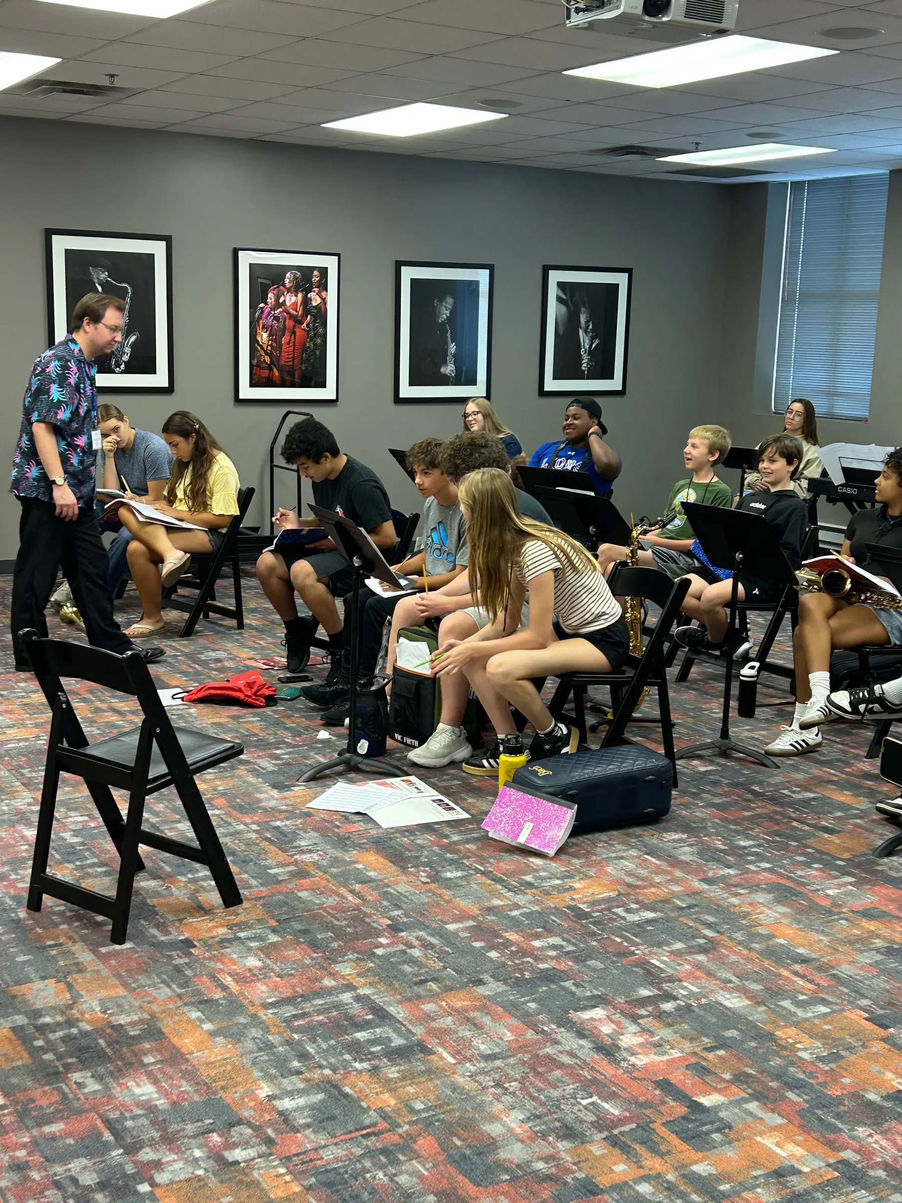 An instructor leads a classroom discussion with seated students and their instruments.
