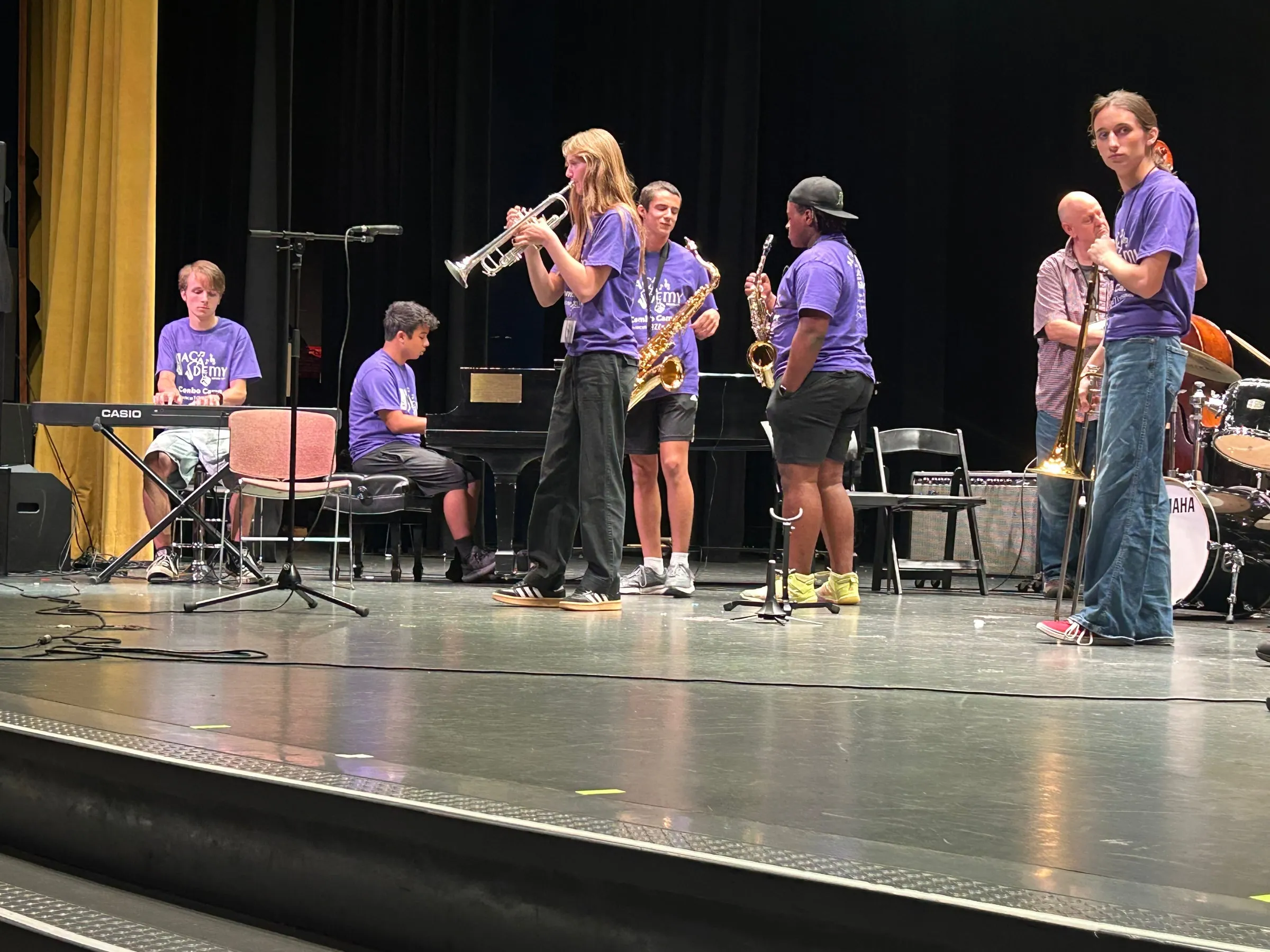 A trumpet player performs with a small ensemble of saxophones, keyboards, and rhythm players onstage.