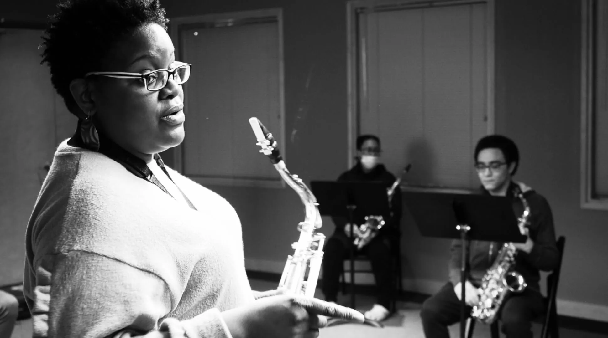 An instructor holds a saxophone while teaching two student saxophonists at the Kansas City Jazz Academy.