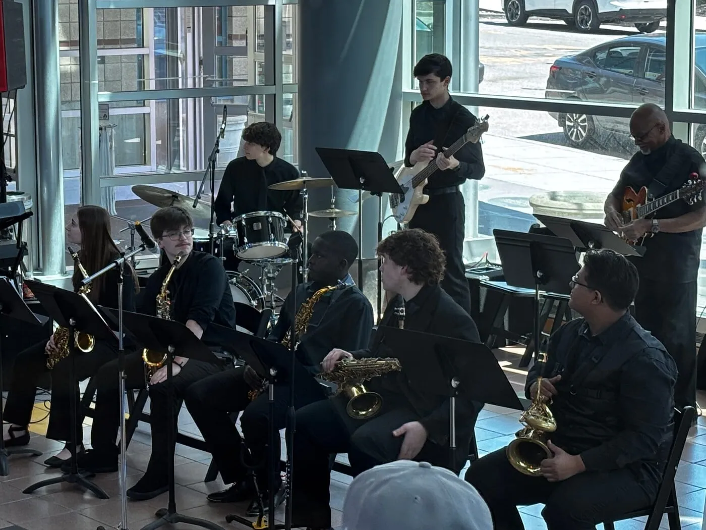 The Williams Combo performs by tall windows, five saxophonists seated in front of drums, bass, and guitar.
